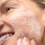 Close-up of a person applying The Body Shop Tea Tree Facial Wash to their face.