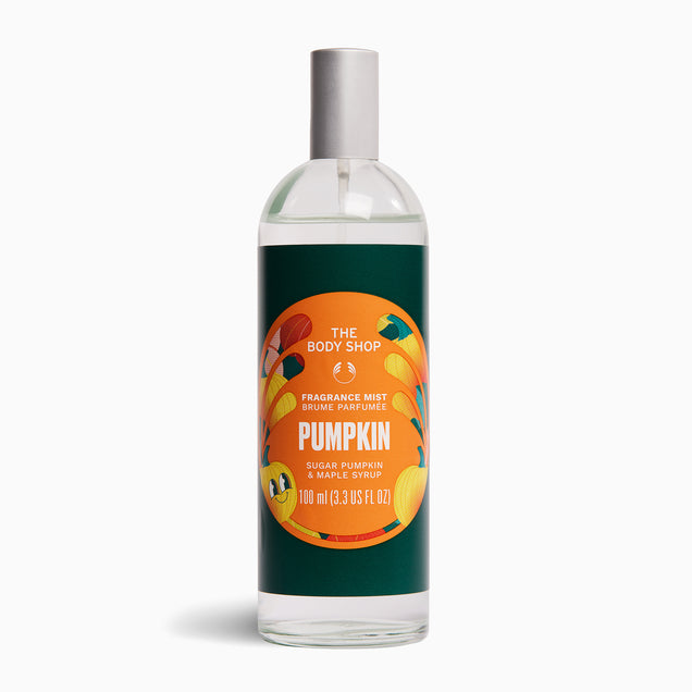 A bottle of The Body Shop Pumpkin Fragrance Mist spray, featuring a dark green label with a circular orange and yellow pumpkin graphic, and a silver spray cap, set against a plain white background.