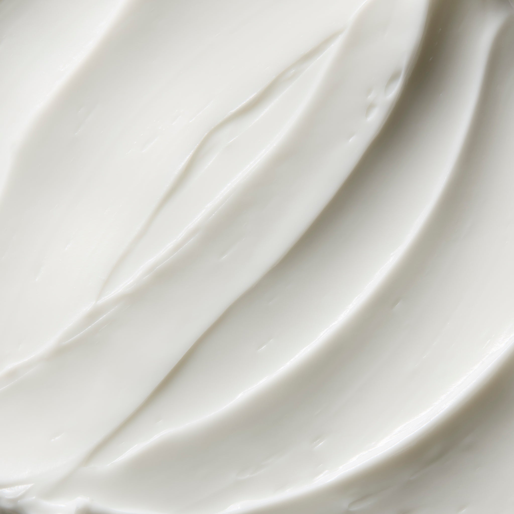 Close-up of smooth white almond milk body butter cream, showing soft swirls and a rich, creamy texture | The Body Shop
