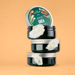 A collection of body butter jars arranged on top of each other with the lid of the Shea jar showing | The Body Shop