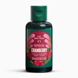 A bottle of The Body Shop Cranberry Shower Gel, 60 ml, featuring a dark green bottle and cap with a label depicting red cranberries on a white background.