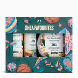 The Body Shop Shea Favourites gift set in a decorative teal box with colorful illustrated motifs, containing three Shea products: body cream, hand balms, and body butter.