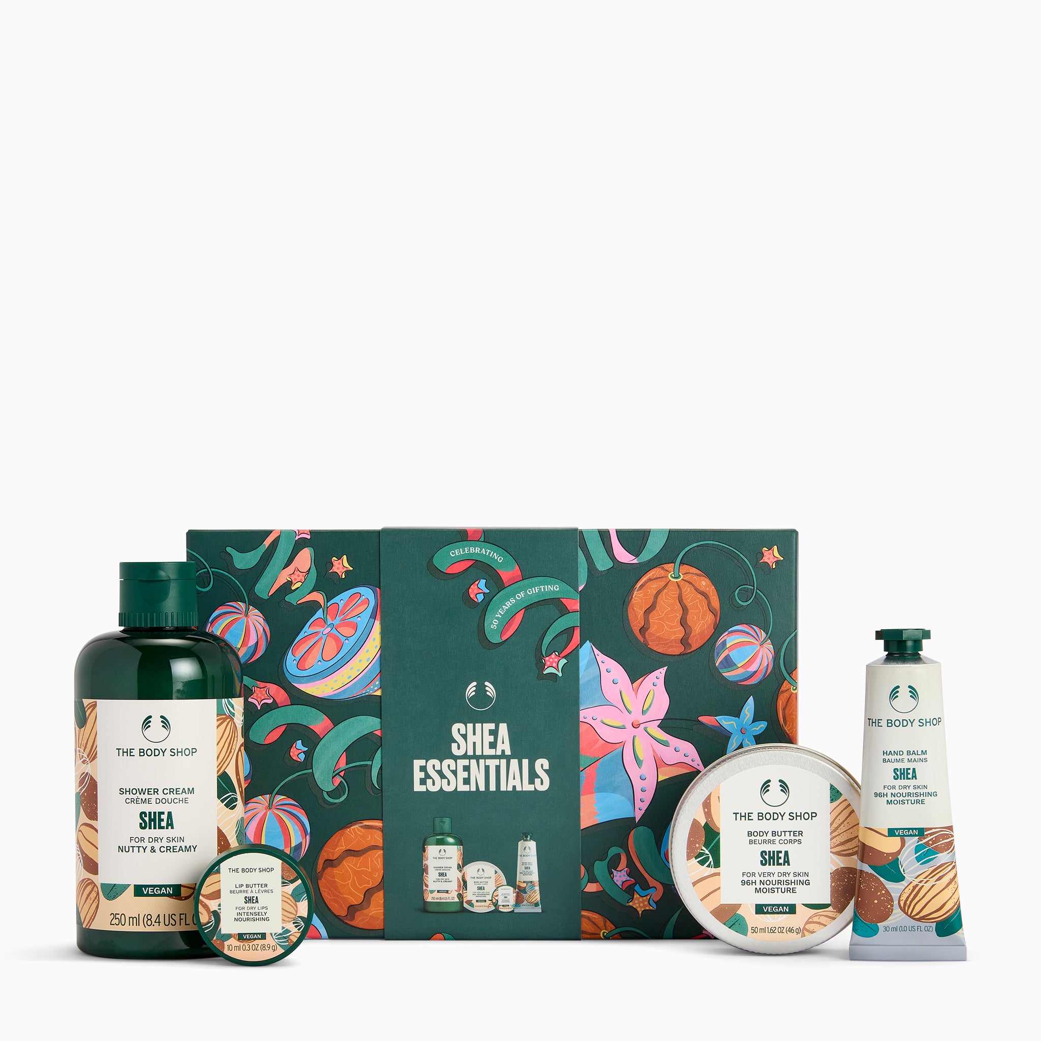 The Body Shop Shea Essentials gift set featuring a dark green shower cream bottle, hand cream tube, bath & body scrub bottle, round tin, and a decorative illustrated gift box on a white background.