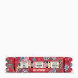 The Body Shop Body Butter Trio in a decorative red Christmas cracker box with colorful illustrations and labels for Shea, Butter Rose, and Almond Milk body butters, shown on a white background.