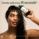 Woman with wet hair holding a bottle of The Body Shop ginger shampoo with text above. Text reads: 1 bottle sold every 16 seconds. Based on global sales of all sizes of Ginger Shampoo between 1st January 2025 and 30th June 2025. Based on 12 hours per day, days per week.