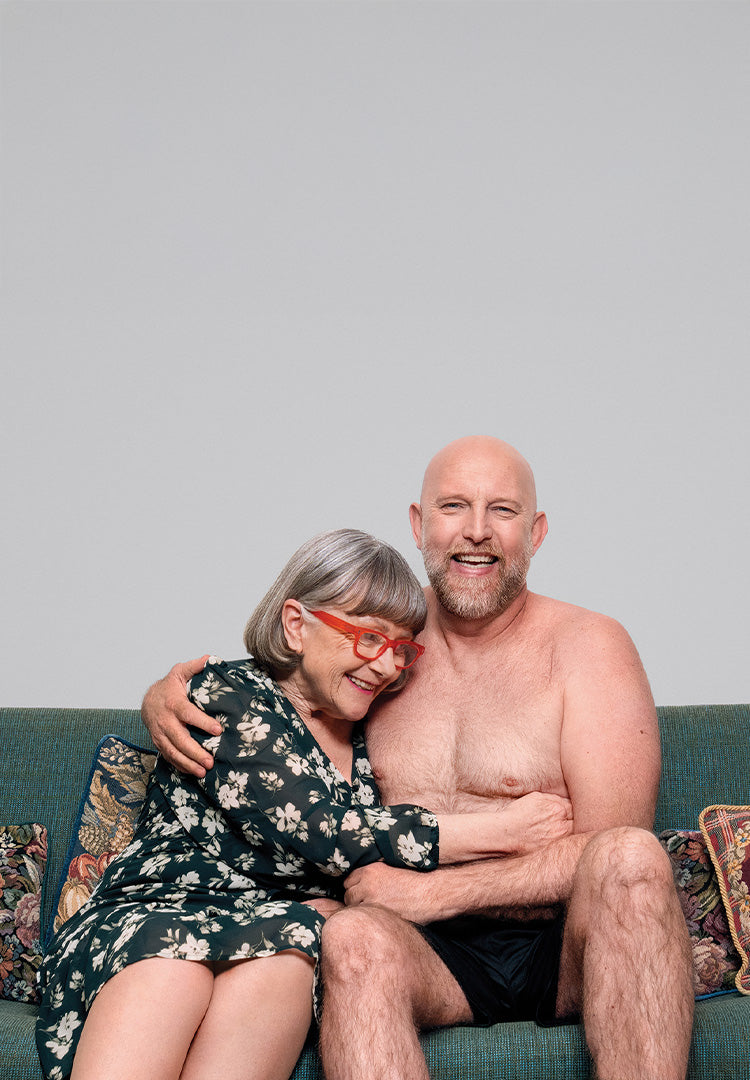 Mother and son sitting on a couch with a plain background